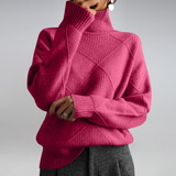 Person wearing a pink turtleneck sweater with a geometric pattern on a plain background
