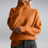 Person wearing a brown turtleneck sweater with geometric pattern on a plain background