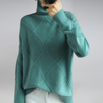 Teal knitted sweater worn by a person on a plain background
