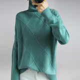 Teal knitted sweater worn by a person on a plain background