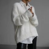 Person wearing a white oversized shirt with a plain background
