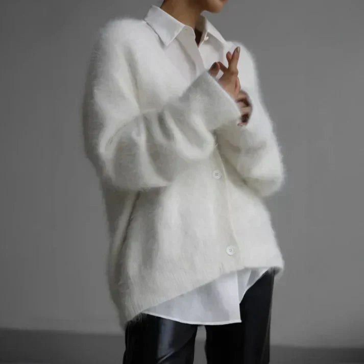 Person wearing a white oversized shirt with a plain background